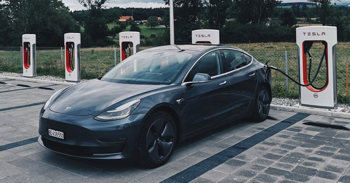 An image of a Tesla car parked up at a Tesla Supercharger station